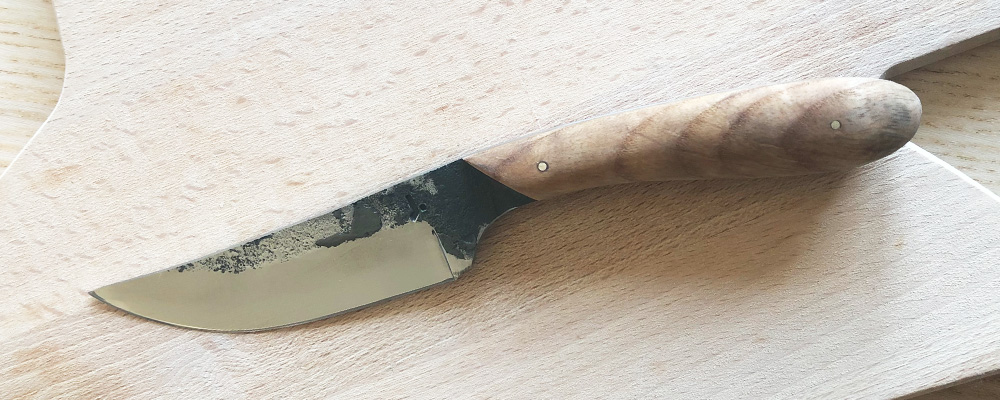 Un couteau artisanal que j'ai forgé et formé, avec un manche en bois et une lame brut de forge